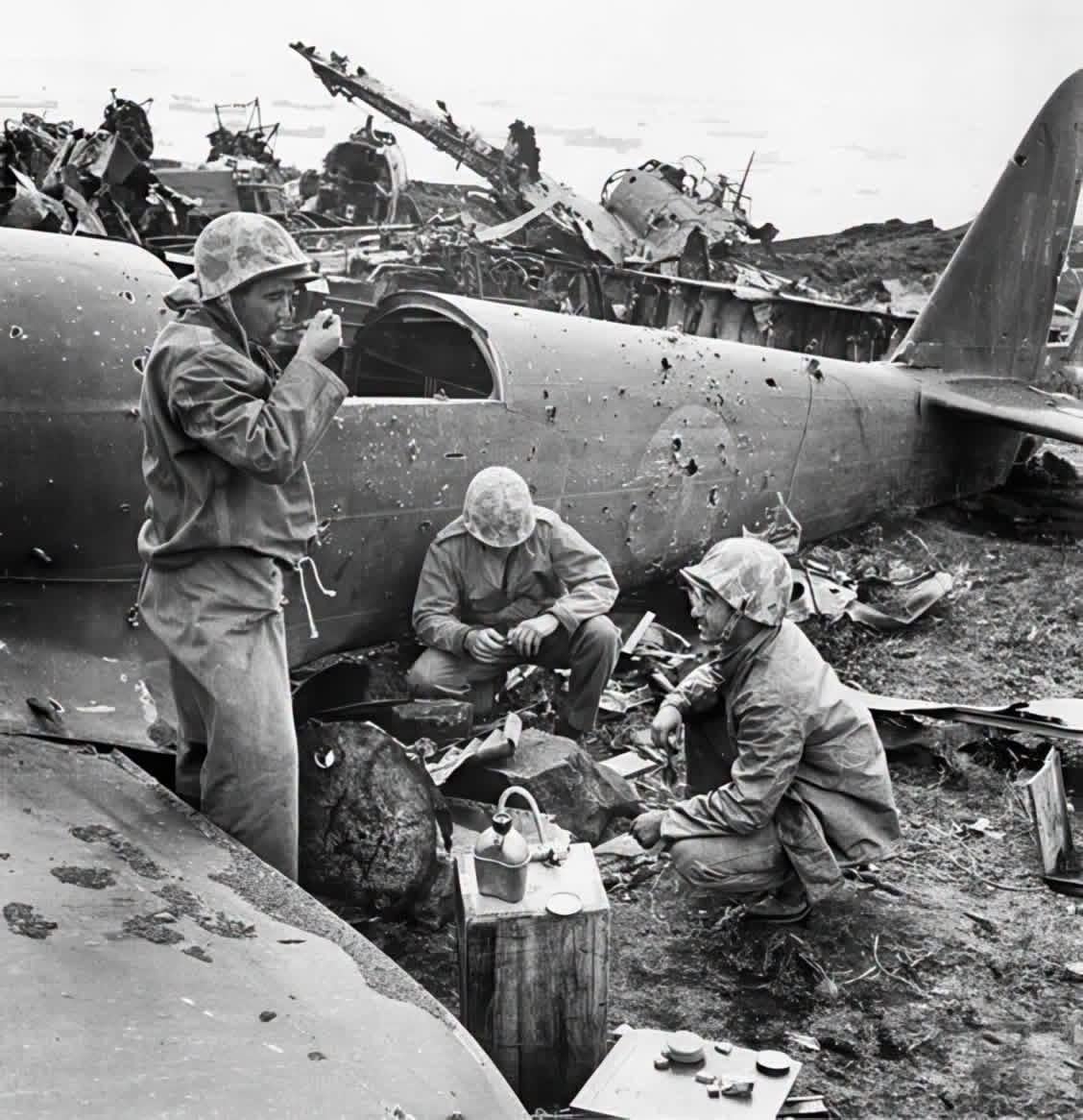 U.S. Marines take a meal break behind the wreckage of a downed Japanese plane during a lull in the fierce battle for Iwo Jima—February 1945. [1128×1166]
