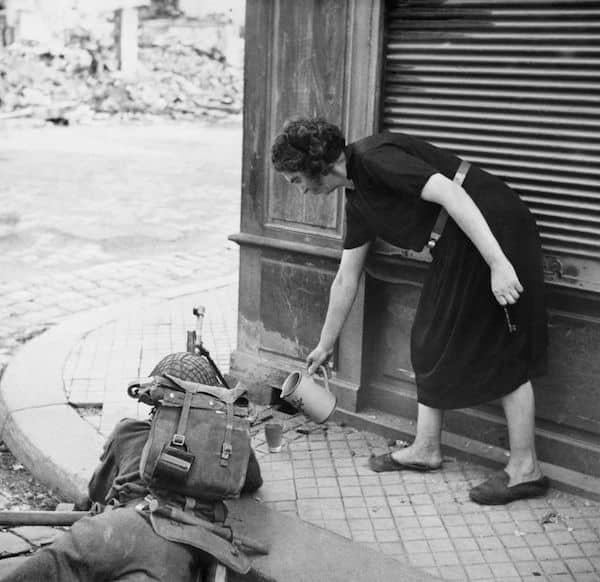 A French civilian woman pours a drink of cider for a British soldier with Bren gun in Lisieux, 1944 [600×582]