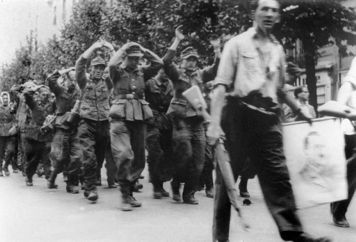 Mocking FFI soldiers carry a portrait of Hitler seized from the Kommandantur headquarters as they lead away captured German soldiers, Paris, August 25, 1944. [1200 × 816]