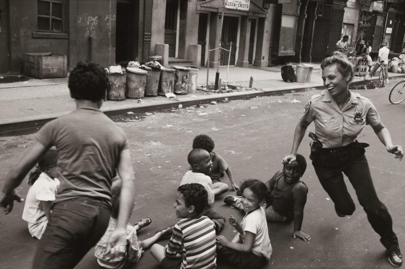 A policewoman in the 9th precinct plays games with community children, New York, 1978.  [1,400×930]