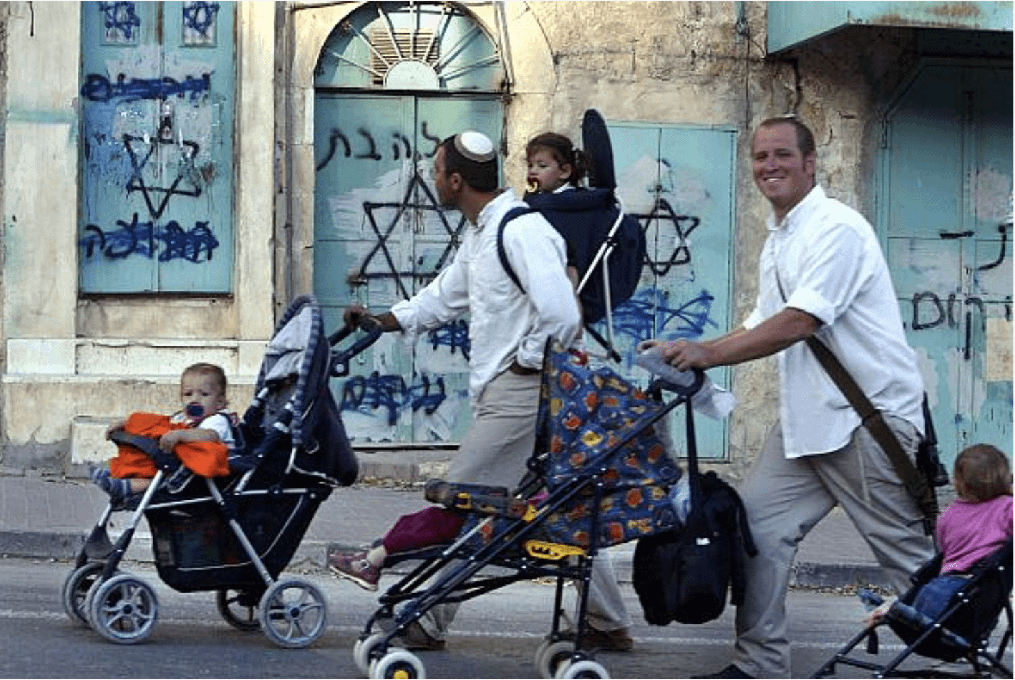 Israeli settlers tour the occupied West Bank town of Hebron during the Jewish religious holiday of Sukkot, passing by settler made graffiti with Kahanist messages. 12 October 2003. [1462 x 980]