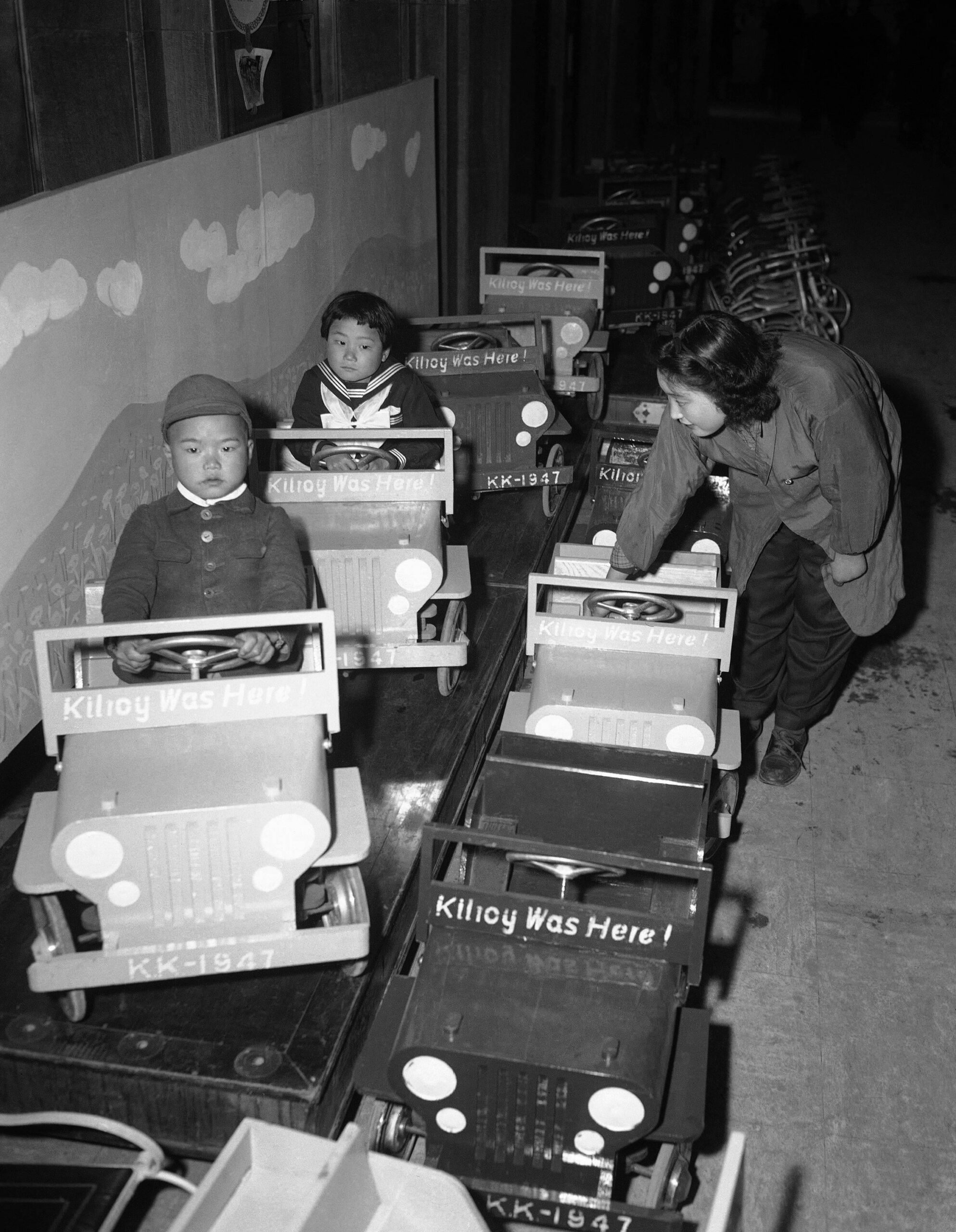 Japanese children visiting a Tokyo department store try out toy jeeps bearing the slogan ‘Kilroy was here’. Japan, 1947. [2329 × 3000]