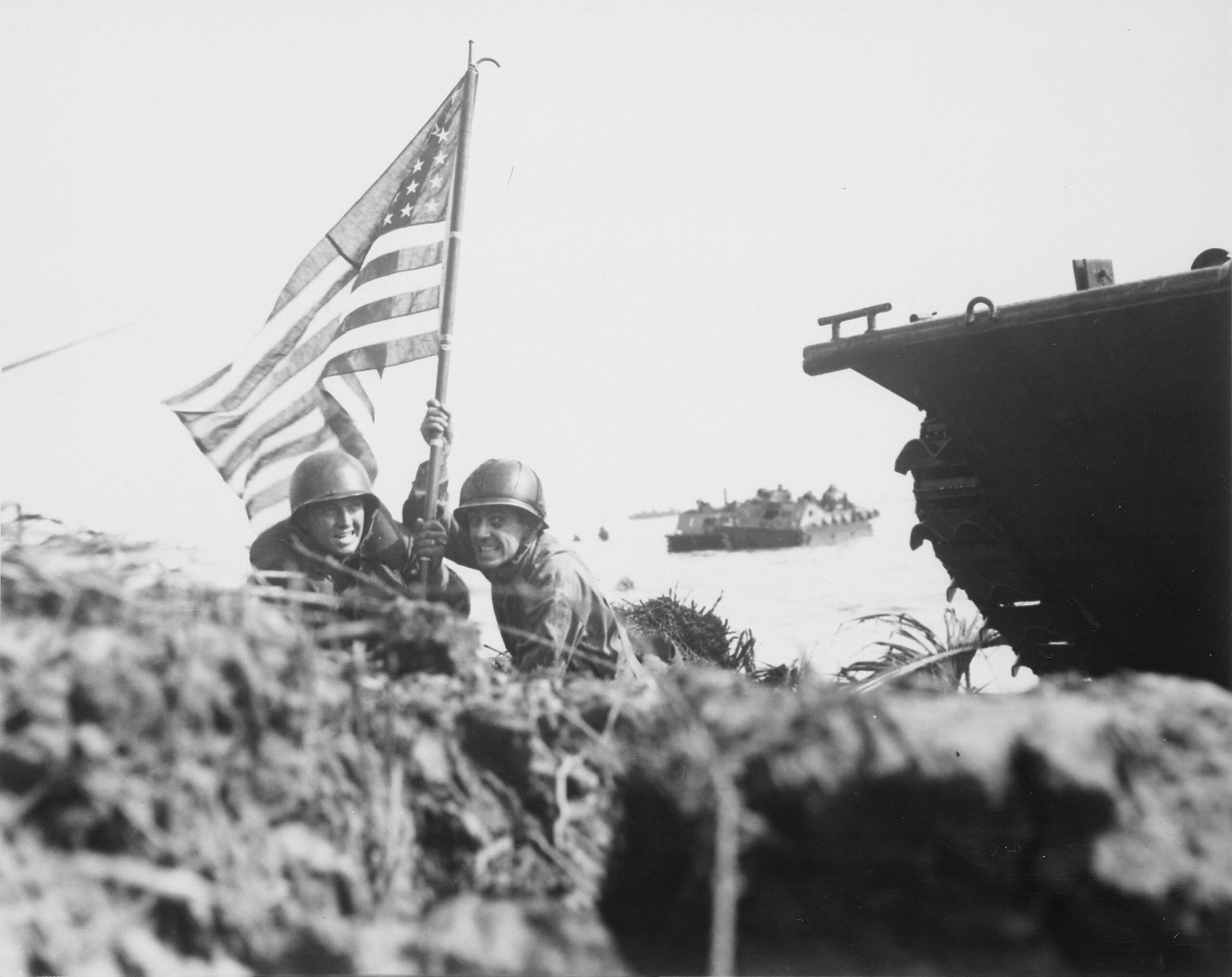 First flag on Guam on boat hook mast. Two U.S. officers plant the American flag on Guam eight minutes after U.S. Marines and Army assault troops landed on 21 July 1944 [3072 × 2435]