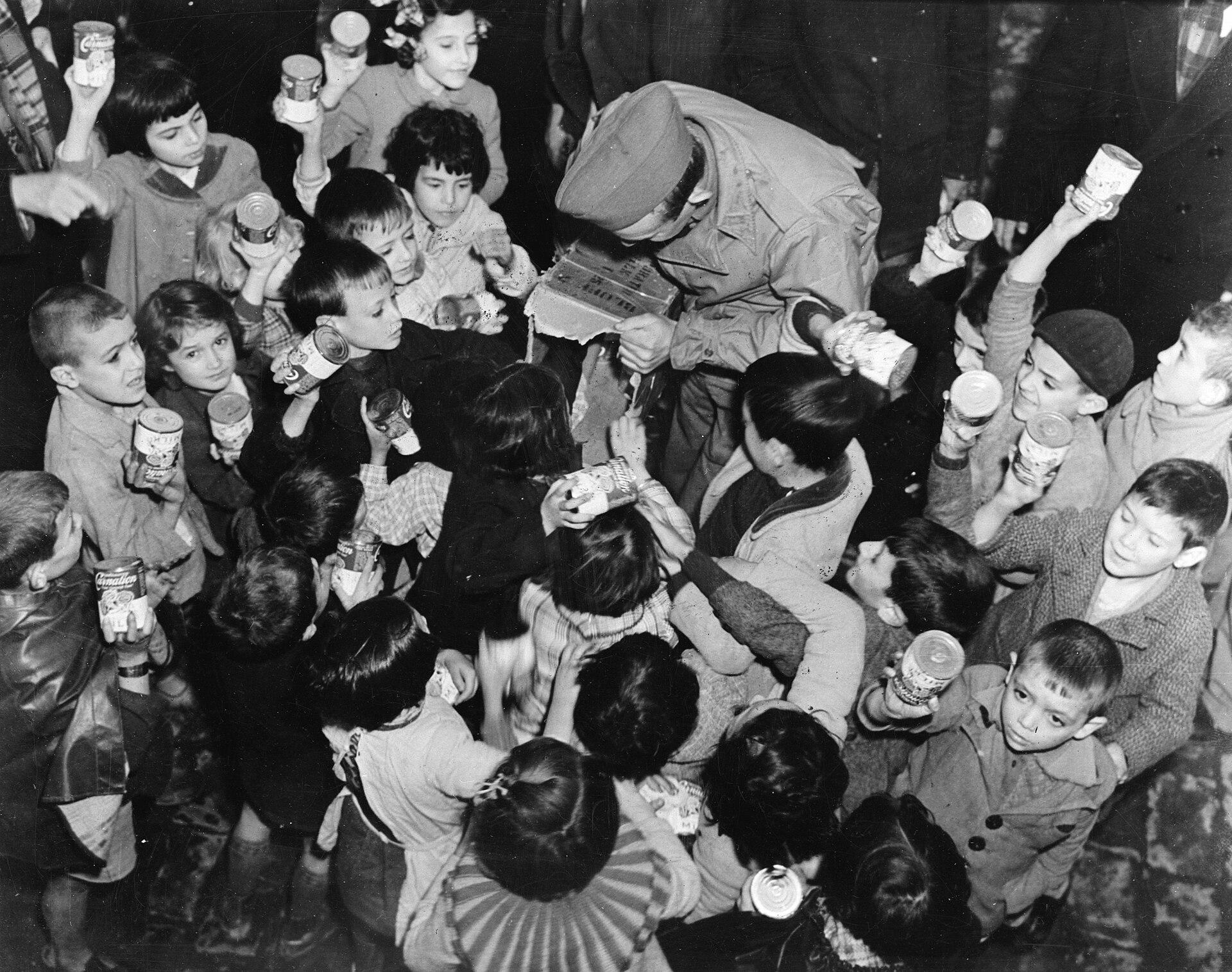 American soldiers distribute milk to French children in Oran, Algeria, c. 1942. The milk came from half of their own military rations. [825×648]