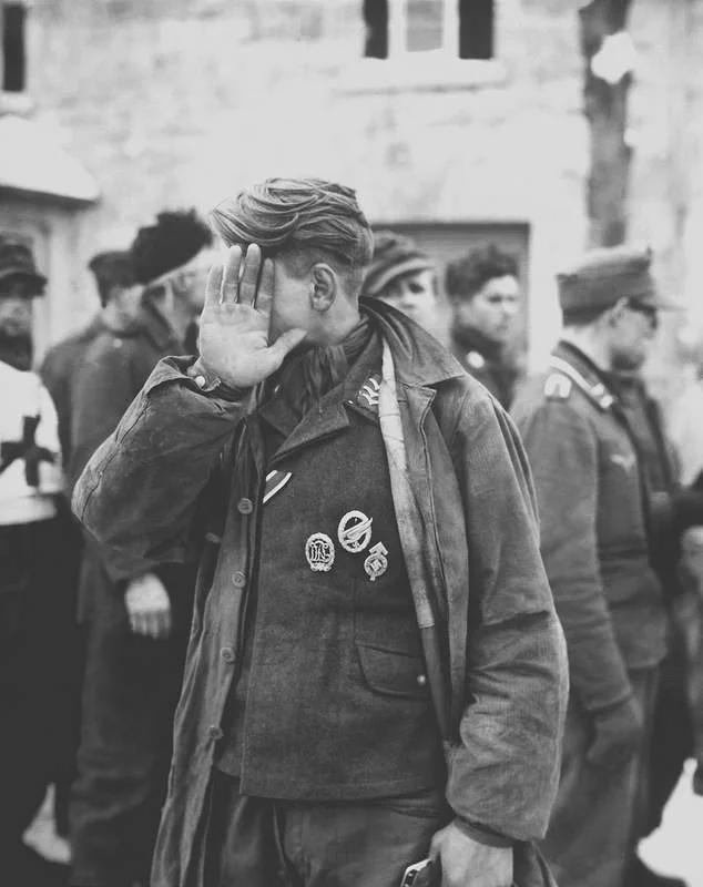 A German soldier shields his face from the camera after he was captured by the US Army’s 16th Infantry near Weywertz, Belgium, 15 January 1945. [634 × 800]